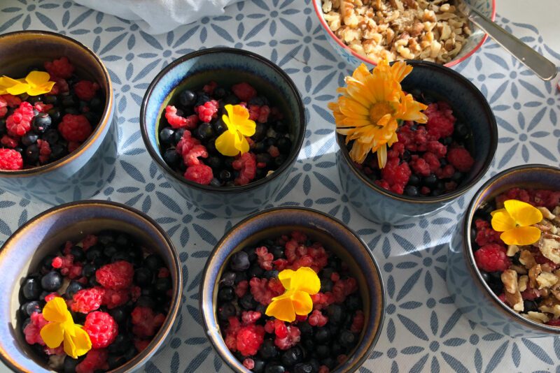 Frukostskålar med färska bär och ätbara blommor under Wise Woman Retreat i Järvsö. 